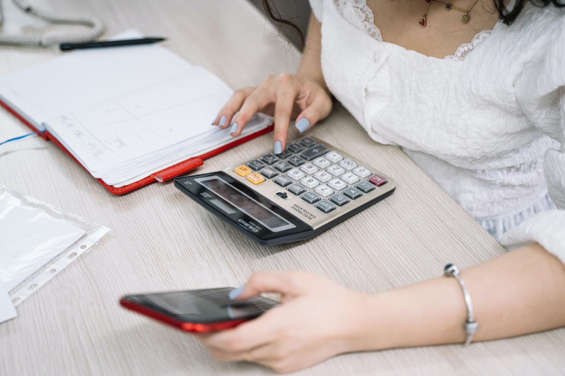 Woman using calculator and holding phone