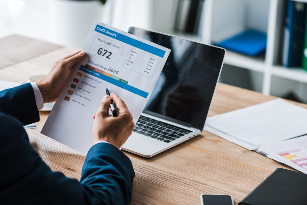 cropped view of man holding pen near paper with credit report letters