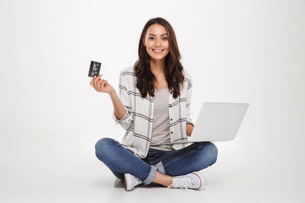smilling woman holding laptop and credit card