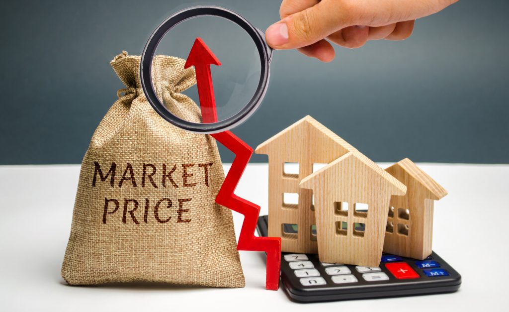 Money bag with the word Market price and an up arrow with a calculator and wooden houses. The concept of increasing housing prices. Rising rent. Real estate market growth