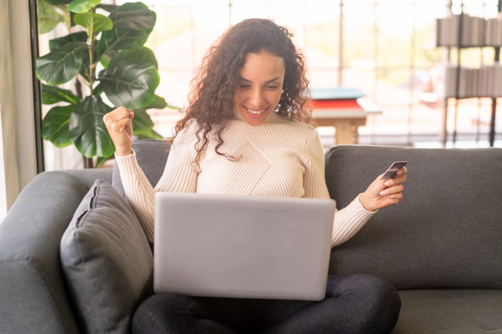 Latin woman using laptop and hand holding credit card for shoppi