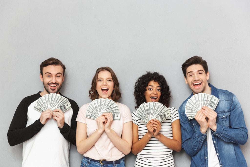Excited group of friends looking camera holding money.