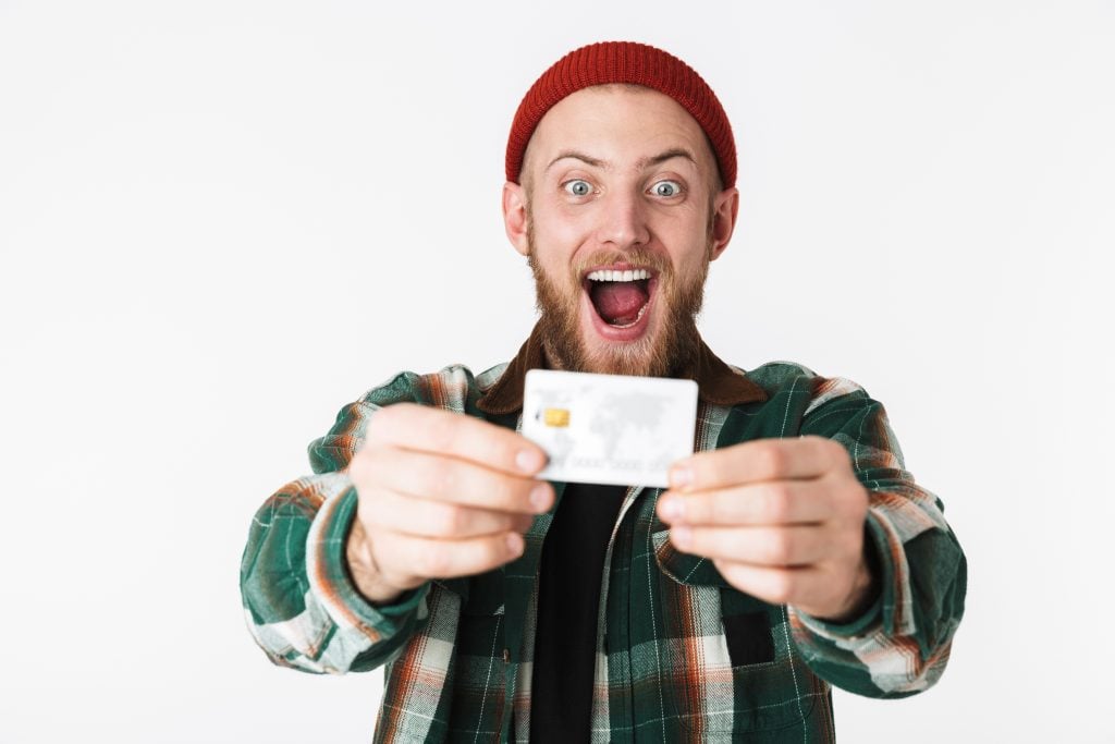 Portrait of hipster man laughing and holding credit card, while
