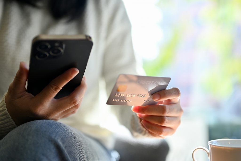 Young Asian woman holding her mobile phone and her credit card. close-up hands image