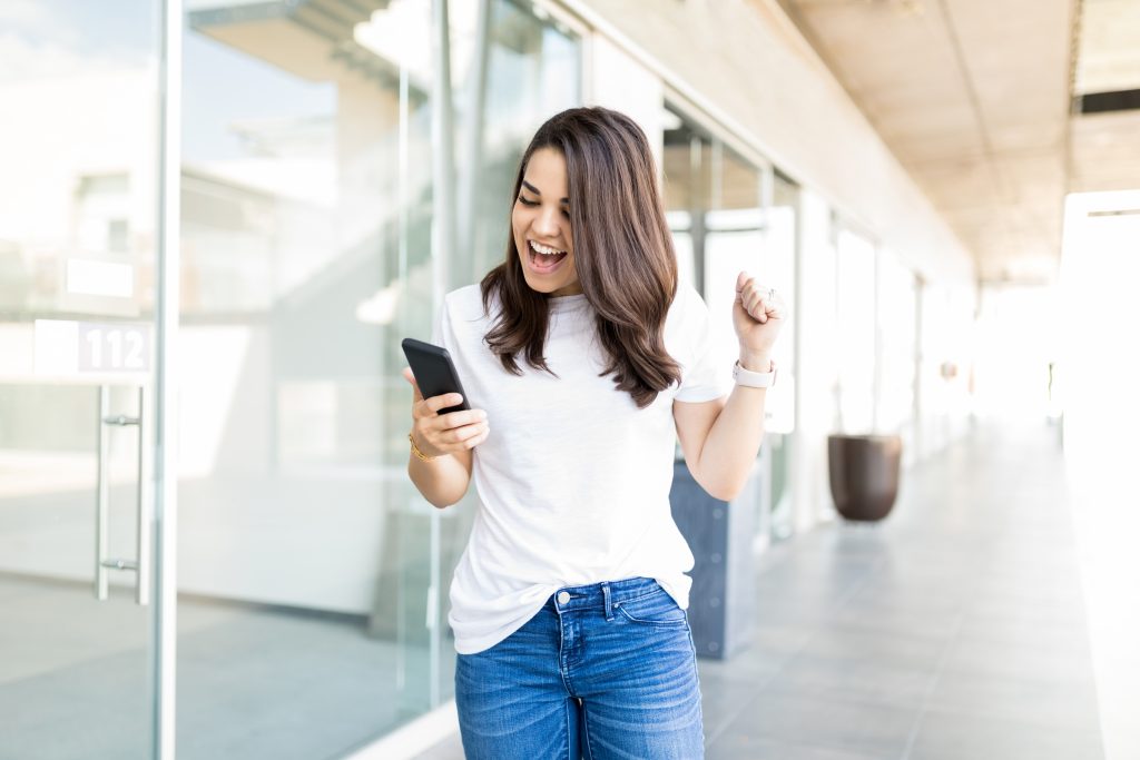 Excited Woman Reading Amazing News In Smartphone