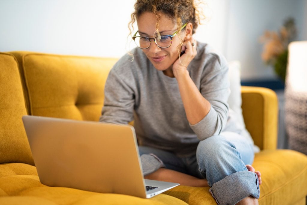 Female sitting on a yellow couch using laptop and internet conne