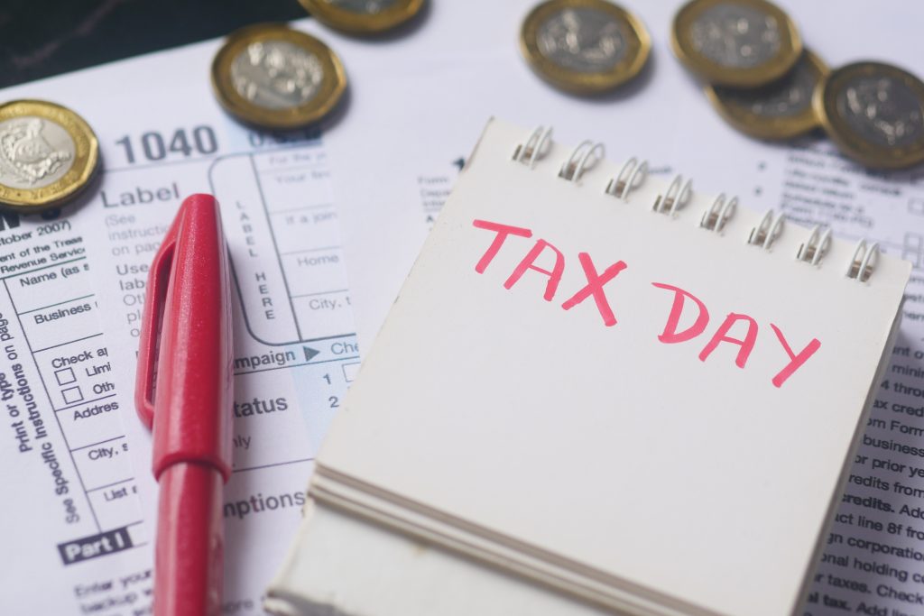 Tax return form and hand written tax day text on a calendar on table