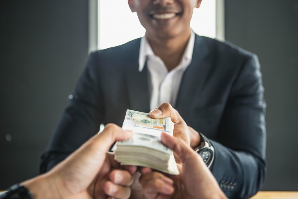 Man offering batch of hundred dollar bills. Hands close up. Vena