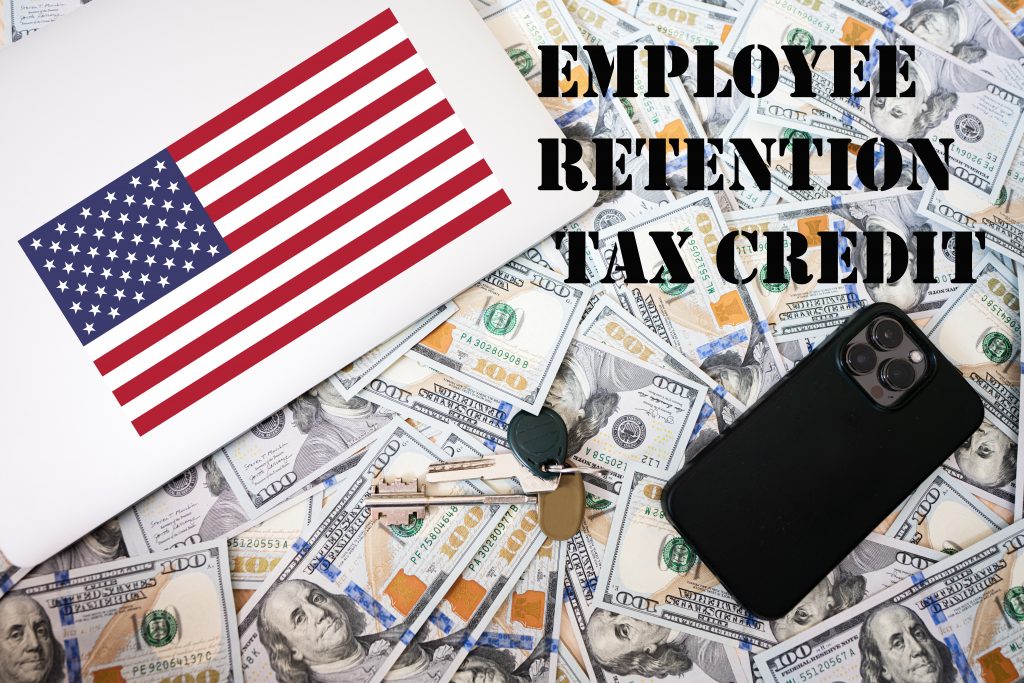 Employee retention tax credit concept. USA flag, dollar money with keys, laptop and phone background.
