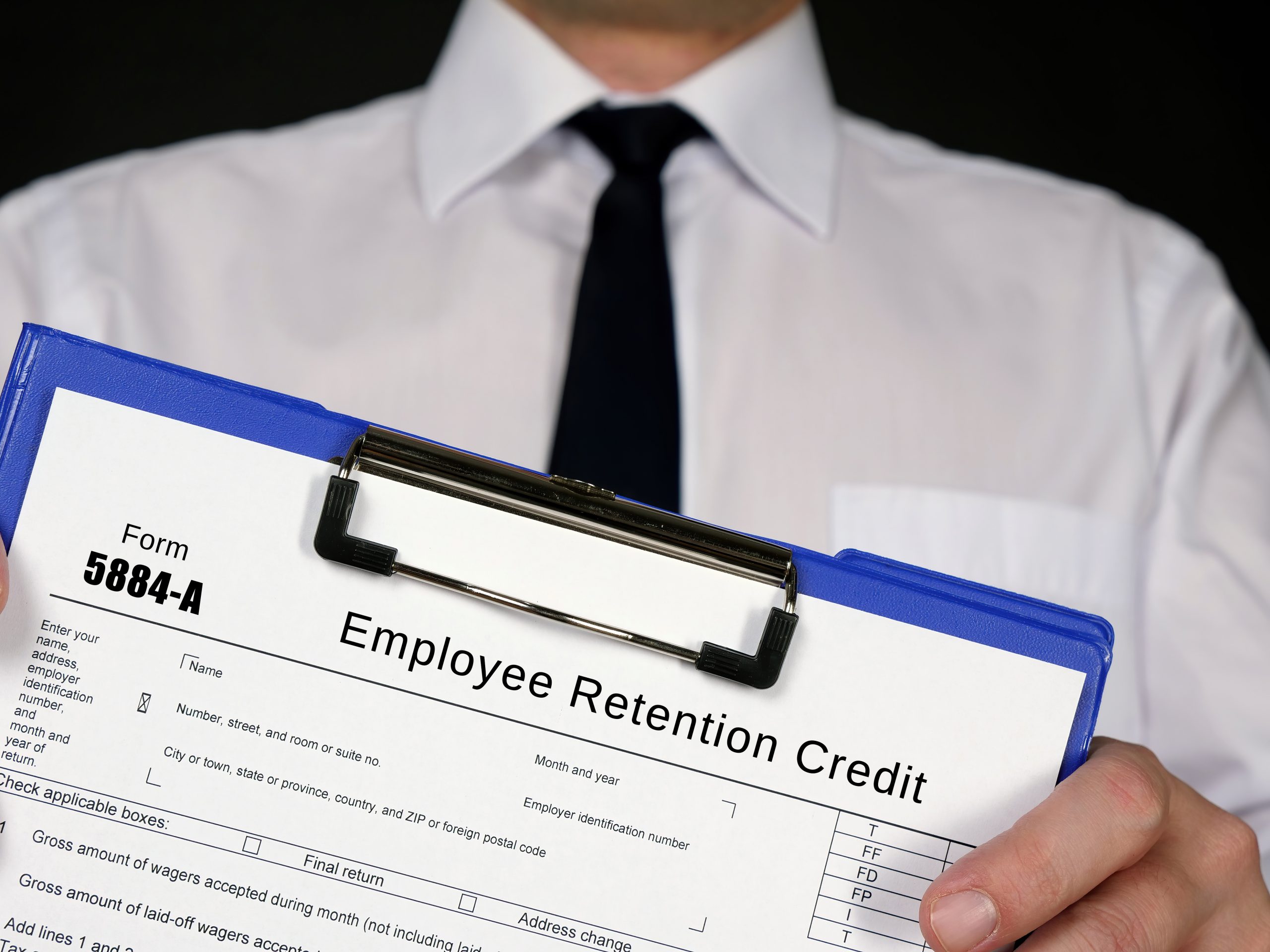 Person in formal wear holding a Form 5884-A Employee Retention Credit.
