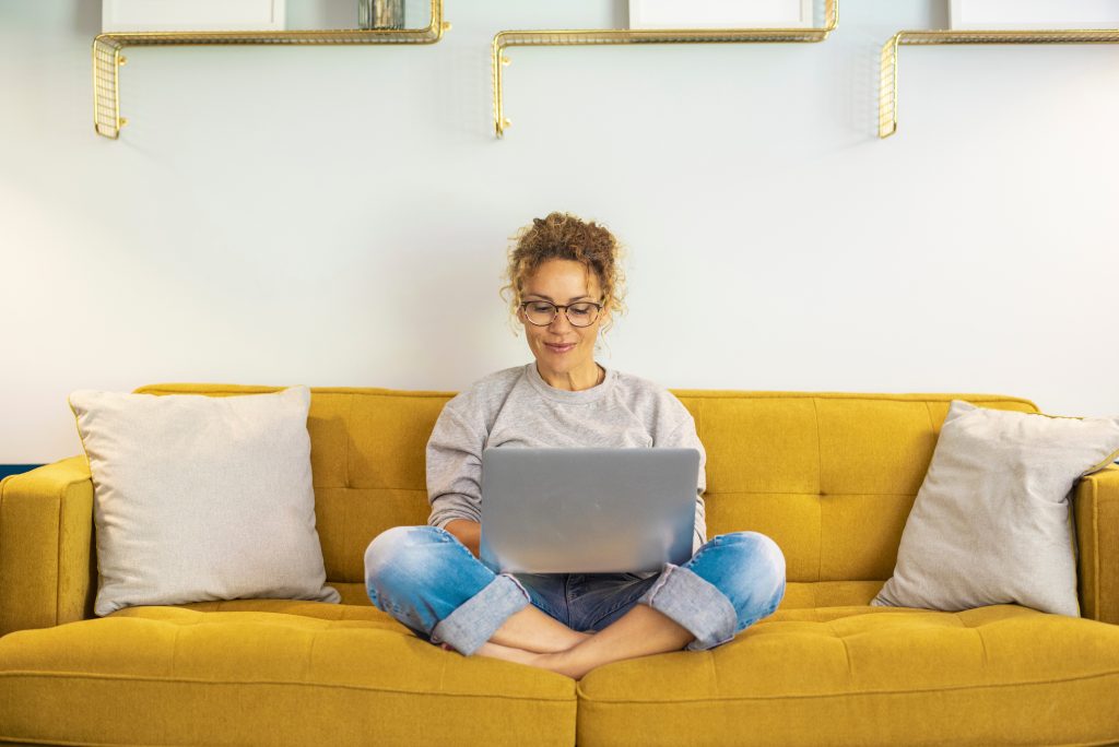 One woman smiling and using laptop computer at home sitting comf