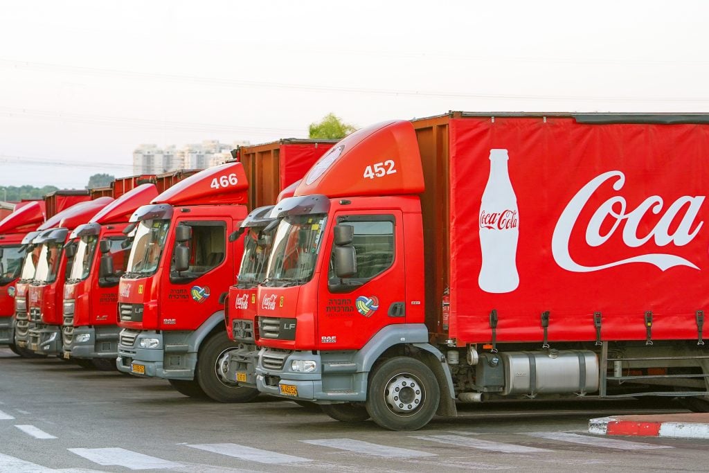 A row of red Coca Cola trucks at a discharge station.