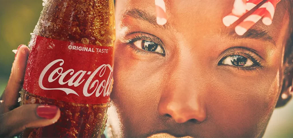 closeup of a woman's face holding a coca-cola drink