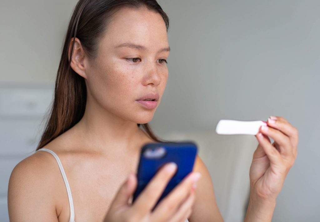 A woman waiting for pregnancy test results, holding her phone.