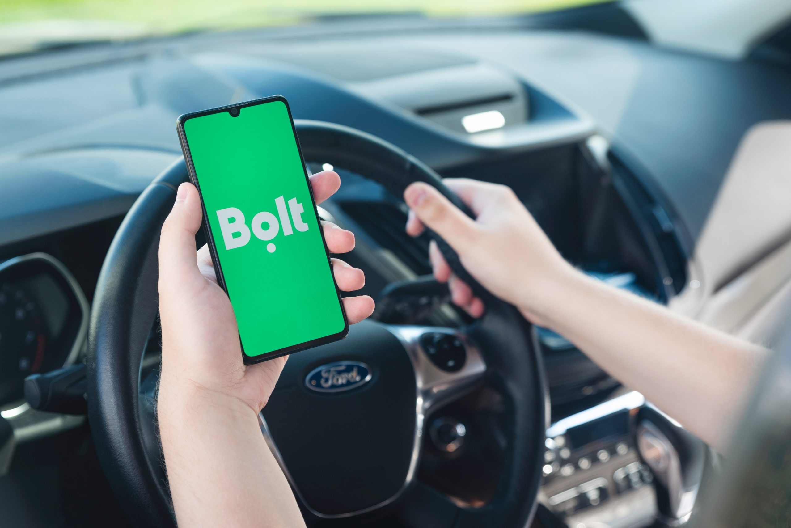 Bolt driver holding smartphone in car